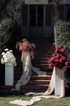 the bride's dress is draped over her veil and flowers are on the steps