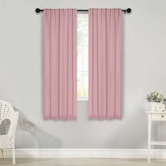 pink curtains hanging on the wall in front of a chair and table with white chairs