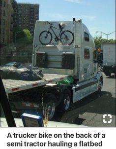 a white truck with a bicycle on the back of it's flatbed in traffic