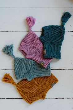 three knitted hats laying next to each other on top of a white wooden floor