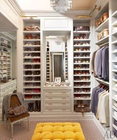 a walk in closet with lots of shoes on the shelves and a bench underneath it