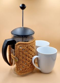 two coffee cups and a crocheted mug cozy