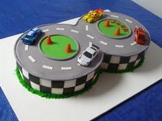 two cakes decorated to look like cars on a race track with traffic cones around them