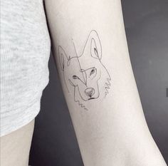 a woman's arm with a small tattoo of a wolf on the left forearm