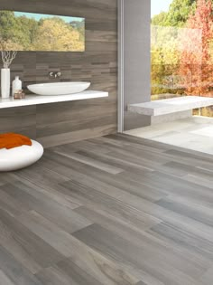 a modern bathroom with wood flooring and white sink, large mirror on the wall