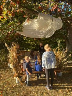 children are gathered around a picnic table under a canopy