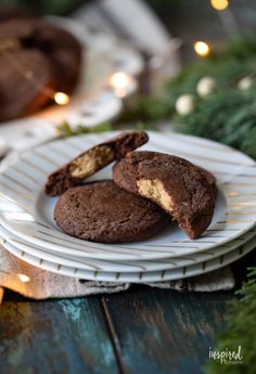 two chocolate cookies on a white plate with christmas lights in the background