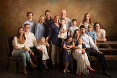 a large family poses for a portrait in front of a wooden bench