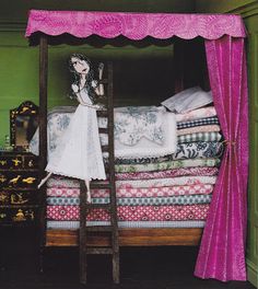 a woman standing on top of a bed next to a pile of blankets and pillows