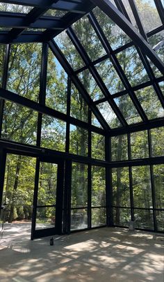 an empty room with glass walls and trees in the background