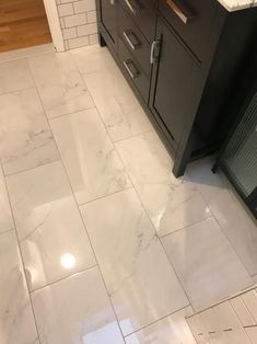 a bathroom with white marble floors and black cabinetry in the corner, next to a sink