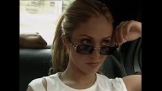 a woman wearing sunglasses sitting in the back seat of a car