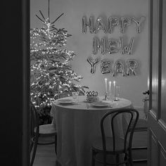 a black and white photo of a dining room with a christmas tree in the corner