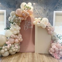 an arch made out of balloons with flowers and greenery on the top for a baby shower