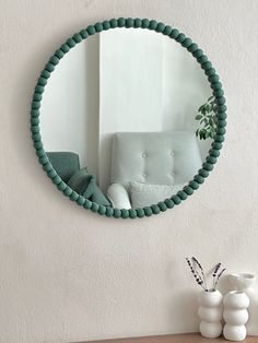 a mirror that is on the wall above a table with a vase in front of it