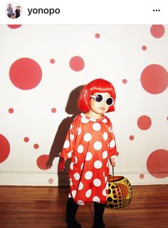 a woman in a red and white polka dot dress holding a basket with her hands