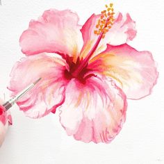 a person is painting a flower with watercolors