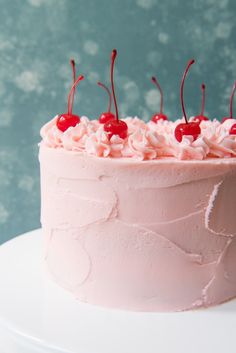 a cake with pink frosting and cherries on top