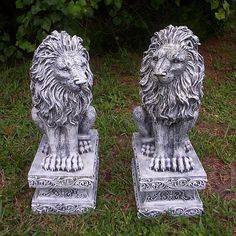 two statues of lions sitting in the grass