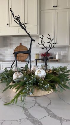 a kitchen with white cabinets and countertops decorated for christmas, including deer figurines