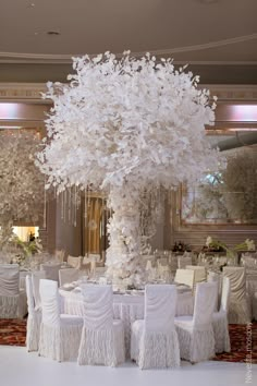 a large white tree is in the middle of a banquet room with tables and chairs