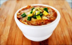 a white bowl filled with soup sitting on top of a wooden table