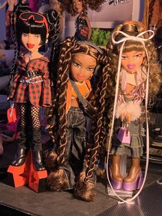 three dolls sitting on top of a table next to each other