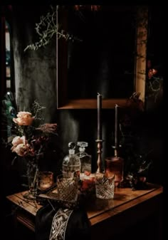 a table topped with bottles and candles next to a mirror on top of a wooden table