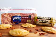 ham and cheese pastries on a wooden cutting board next to packaged sausages, bacon, and bread