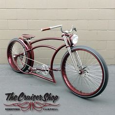 an old fashioned red bicycle is parked in front of a brick wall with the words the cruiser shop written on it