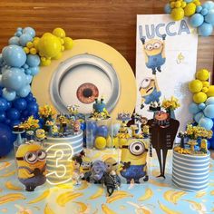 a table topped with blue, yellow and white desserts covered in minion decorations