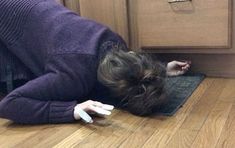 a woman is laying on the floor with her head in the kitchen cabinet door drawer