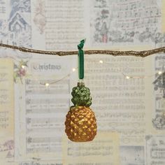 a pineapple ornament hanging from a string with lights on it and music sheets in the background