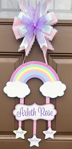 a door hanger with a rainbow and clouds on it that says, arreth rose