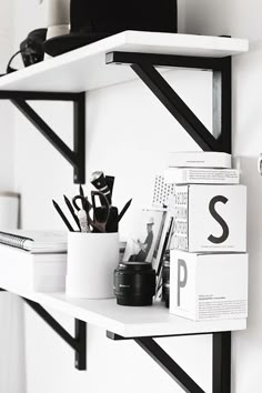 a shelf with some books and other items on it in a black and white room