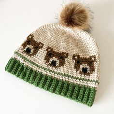 a knitted hat with bears on it and a brown pom - pom