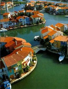 an aerial view of houses and boats on the water in a city with orange roofs