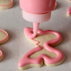 pink icing being used to decorate cookies