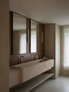 an empty bathroom with two sinks and mirrors