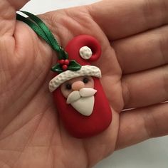 a hand holding a christmas ornament with santa clause on it's head