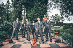 a group of men in suits standing on top of a checkered chess board surrounded by trees