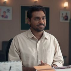 a man sitting at a desk with a binder in front of him and papers on the table