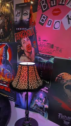 a lamp that is on top of a table next to some pictures and posters in the background