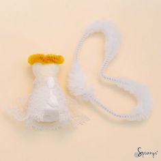 a white doll with a yellow hat on it's head next to a string