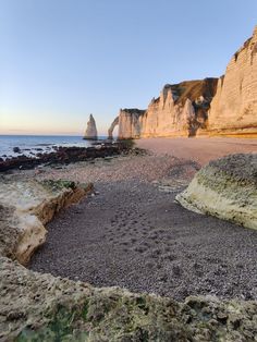 an empty beach with rocks and cliffs in the background