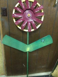 a purple and yellow windmill sitting on top of a green pole in front of a wooden door