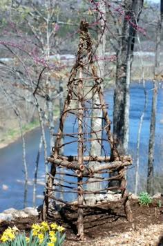 a wooden structure made out of sticks and branches in the woods next to a river