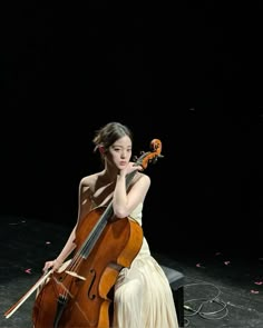 a woman in a white dress is playing the cello