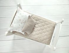 a baby crib with two pillows and a blanket on it's sides, against a white wood background