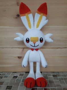 a crocheted stuffed animal sitting on top of a tile floor next to a wooden wall